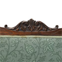 Edwardian mahogany framed sofa, shaped cresting rail with scroll terminals and carved foliate pediment, upholstered back and swept arms in green foliate fabric, pierced splat supports, serpentine front seat rail, on cabriole supports terminating in castors