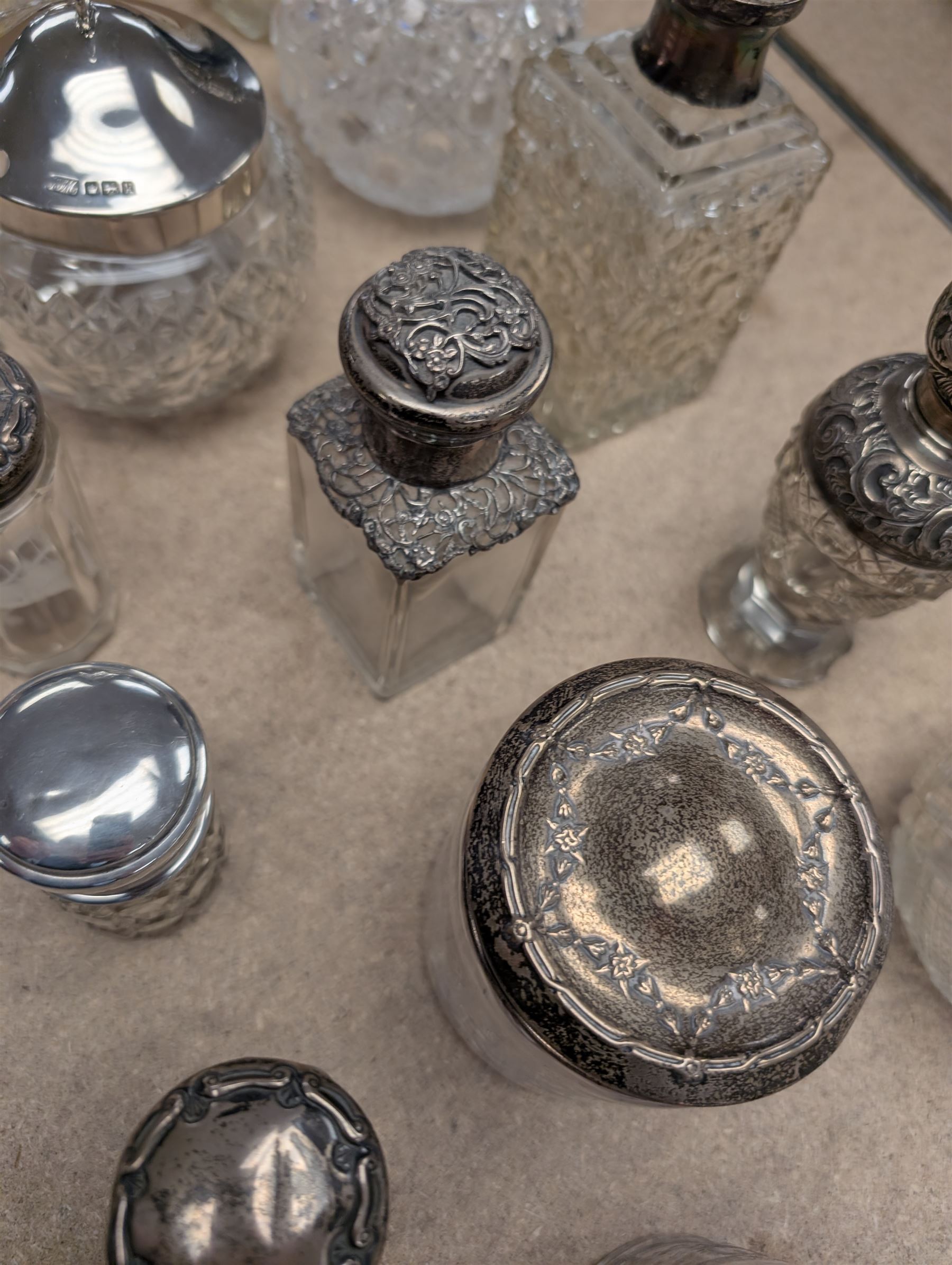 Collection of silver mounted glass bottles and jars, including decanter with etched floral decoration and silver collar, four scent bottles with silver caps, etc all hallmarked 