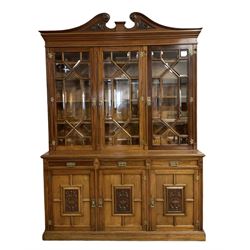 Edwardian mahogany bookcase on cupboard, projecting cornice over three astragal glazed doors with mouldings and bevelled glass, moulded uprights and carved with flower head roundels, the lower section with moulded rectangular top over three drawers and three cupboards, the doors panelled and carved with foliage scrolls and urns, plinth base