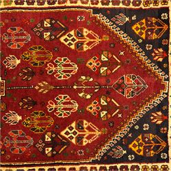 South West Persian Qashqai rug, hand knotted wool with central dark blue lozenge medallion containing geometric motifs, on a madder red field decorated with stylised floral boteh motifs, indigo spandrels, multiple borders of floral rosettes, from the region of Fars, south-west Persia