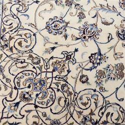 Central Persian Nain hand-knotted carpet, wool with silk highlights, ivory field with central radiating medallion surround by an intricate arrangement of scrolling vines and floral motifs, within conforming spandrels and matching border, cotton fringe ends 