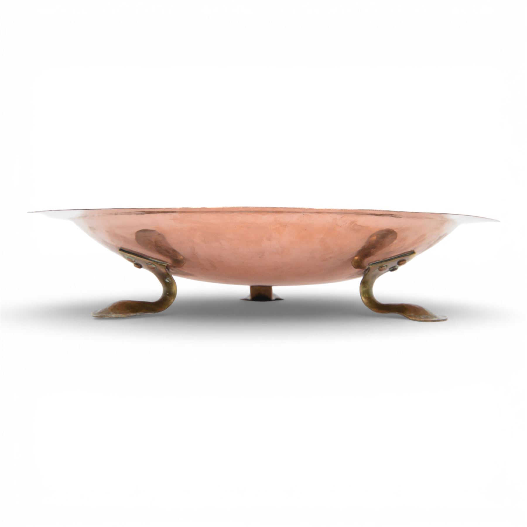 Arts and Crafts Birmingham Guild of Handicraft copper bowl, of circular form, the broad rim stamped with circles and fruiting sprigs, raised upon three cast brass feet, with impressed mark beneath The Birmingham Guild Ltd England, D30cm