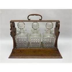 Edwardian oak tantalus, with copper handle, containing with three square cut glass decanters, H32.5cm
