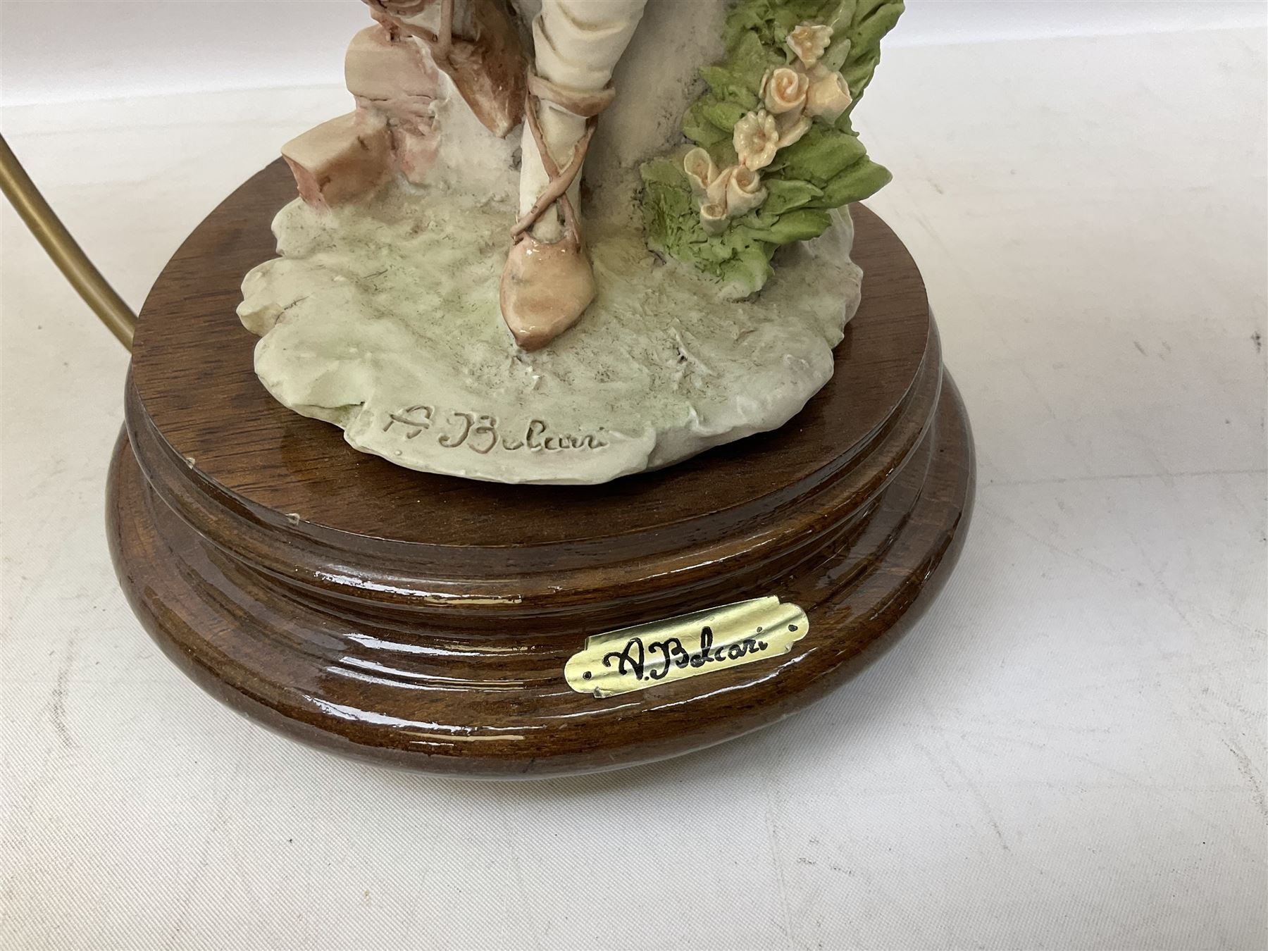 A Belcari figural table lamp, modelled as a young gent leaning upon brick wall, on turned wood base, signed, H70cm incl shade, together with bronzed figural table lamp of a lady with parasol upon ornate circular plinth base, two ceramic table lamps and another lamp (5)