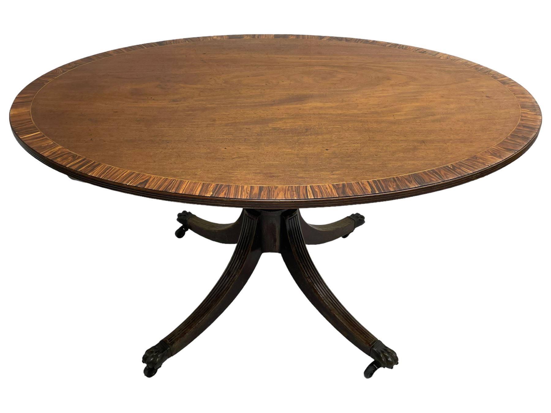 George III mahogany breakfast table, the oval top with a kingwood band and boxwood stringing, raised on a turned vasiform pedestal terminating in a fluted sabre tripod base with hairy paw feet and castors