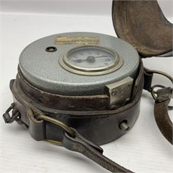 Metal cased drum shaped travelling clock with grey hammered finish, French clockwork movement and stitched leather outer case with shoulder strap; bears manuscript label 'Royal Armament Research and Development Establishment - serial no.09433' D13cm overall