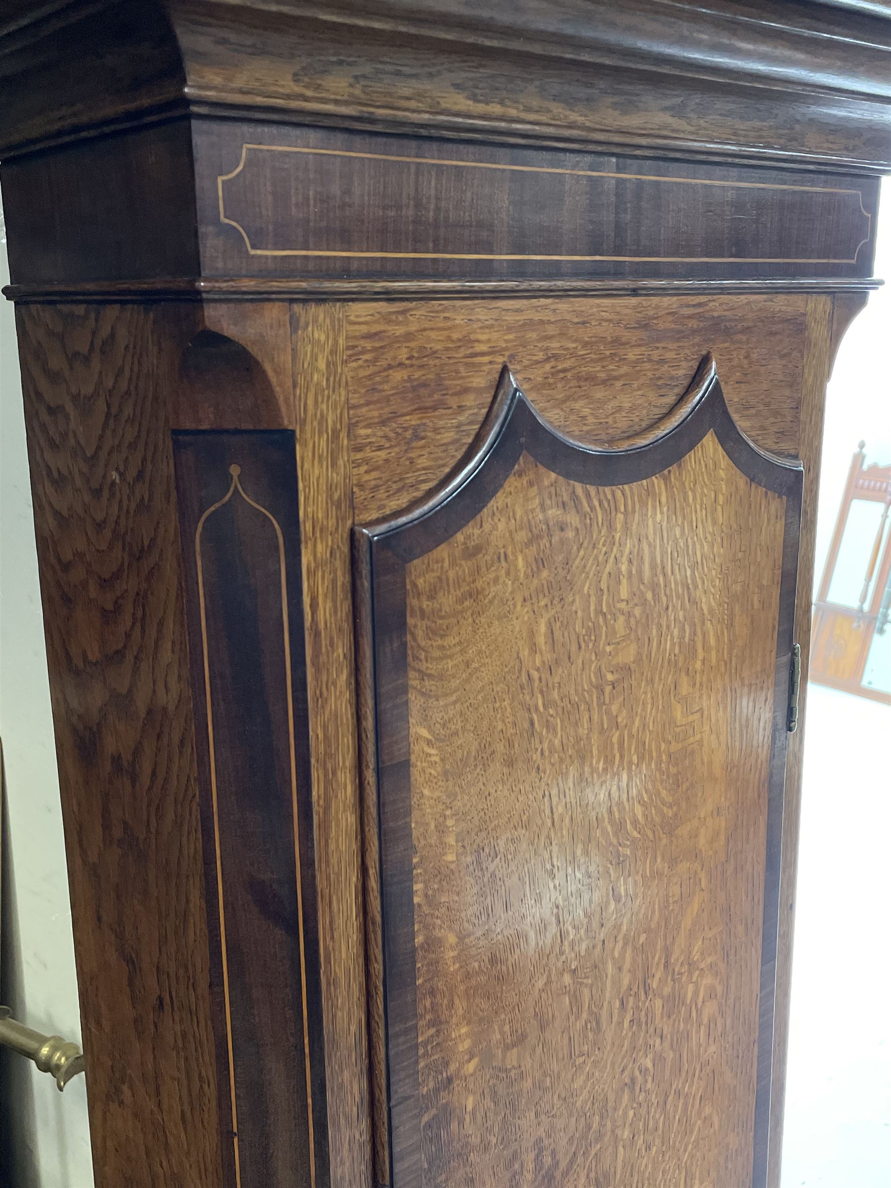 Early 19th century oak and rosewood banded longcase clock, scrolled pediment over stepped arch hood door, enamel painted dial indistinctly signed for a Penrith maker, 30-hour movement striking on bell
