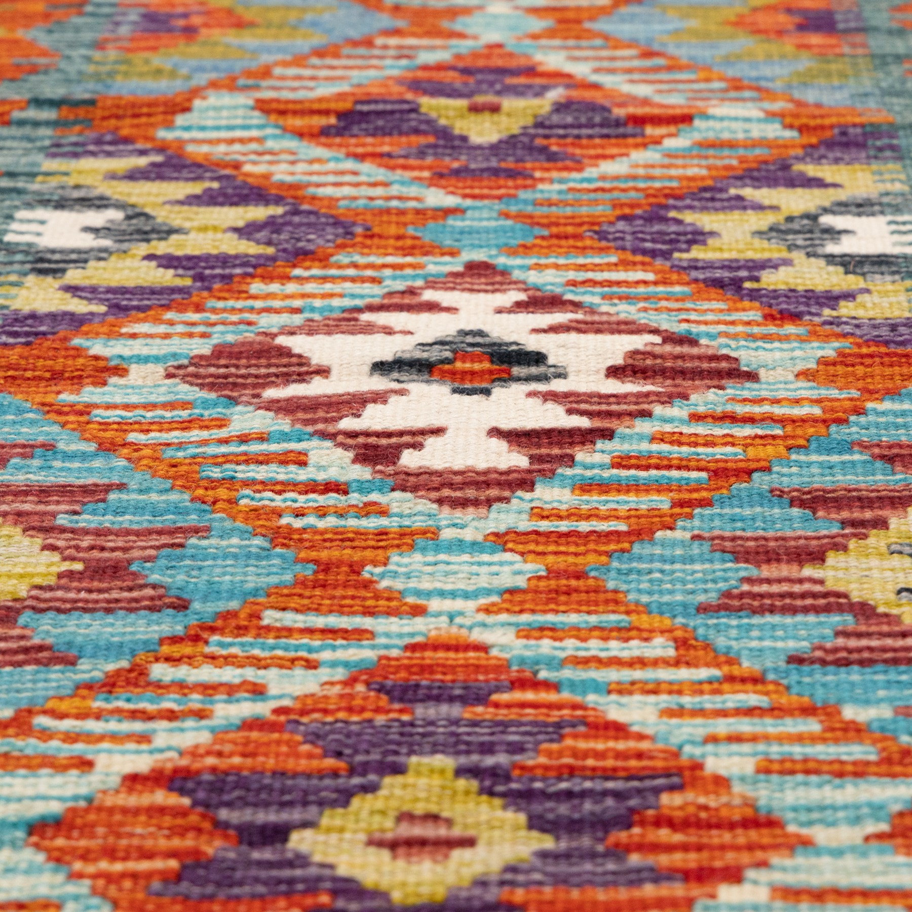 Afghan kilim amber ground runner rug, decorated a central column of repeating lozenge designs in multicolours with concentric geometric motifs, enclosed by an amber guard band with repeating diamond design
