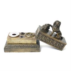 19th-century Grand Tour patinated bronze inkwell, surmounted by a recumbent lion, the beast modelled in the antique manner with one paw resting upon a stack of books, emblematic of strength, learning and guardianship. The stepped rectangular base cast with classical foliate friezes, fitted with multiple apertures and an inset ceramic inkwell and pounce pot; an erudite decorative object in the Grand Tour tradition, drawing on Renaissance and Roman prototypes, W12.5cm H11.5cm