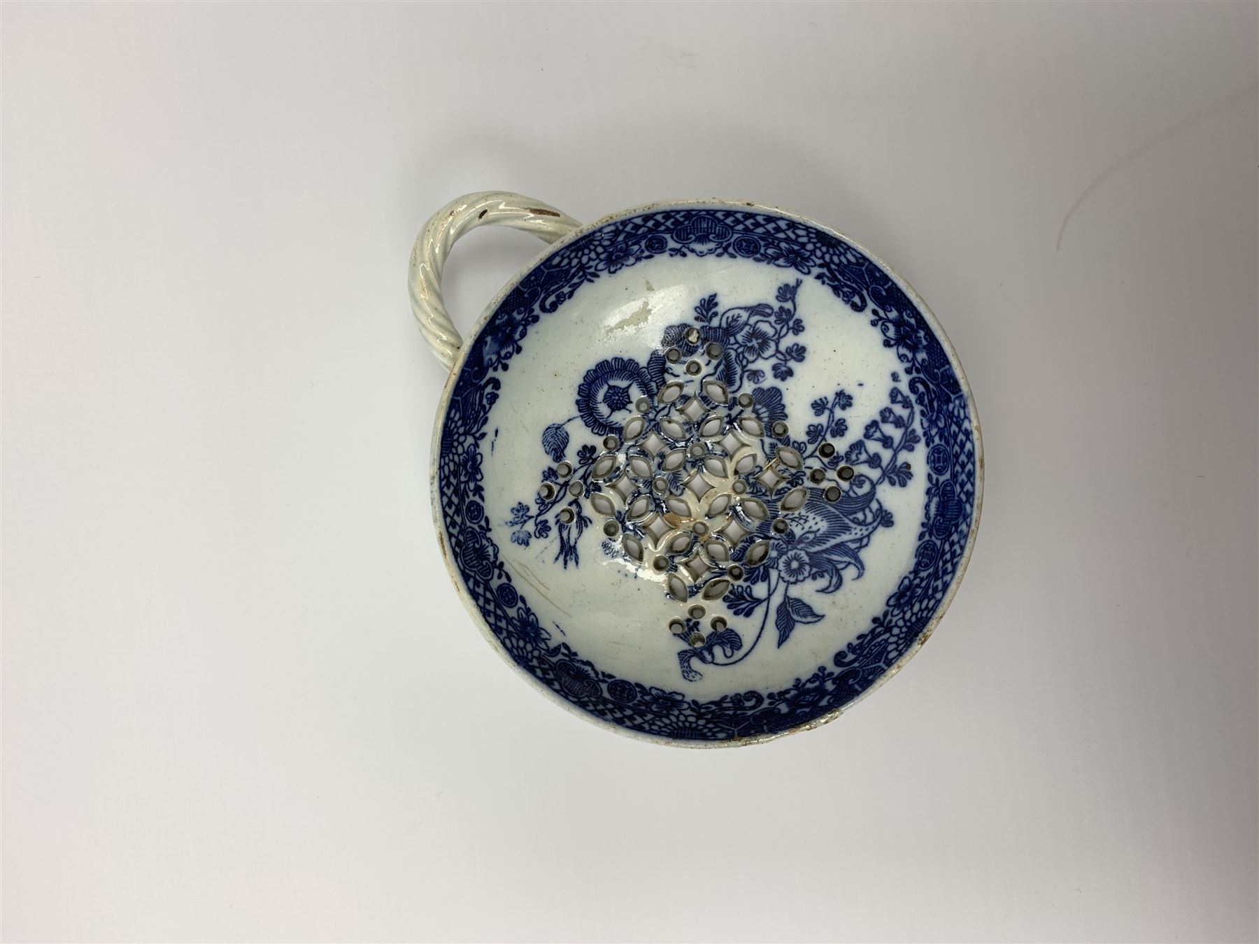 Late 18th/early 19th century Leeds Pottery egg drainer, the pierced bowl of circular form decorated with blue transfer printed floral spray and floral border, the twisted handle with foliate mounts, bowl D9cm