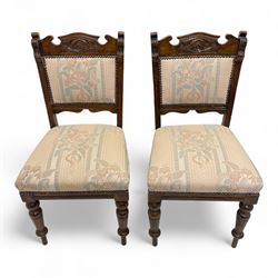 Victorian walnut set of four dining chairs, the shaped and carved top rails with central flowerhead and scroll decoration above upholstered backs and seats in floral woven fabric, brass stud trim, on ring turned front supports