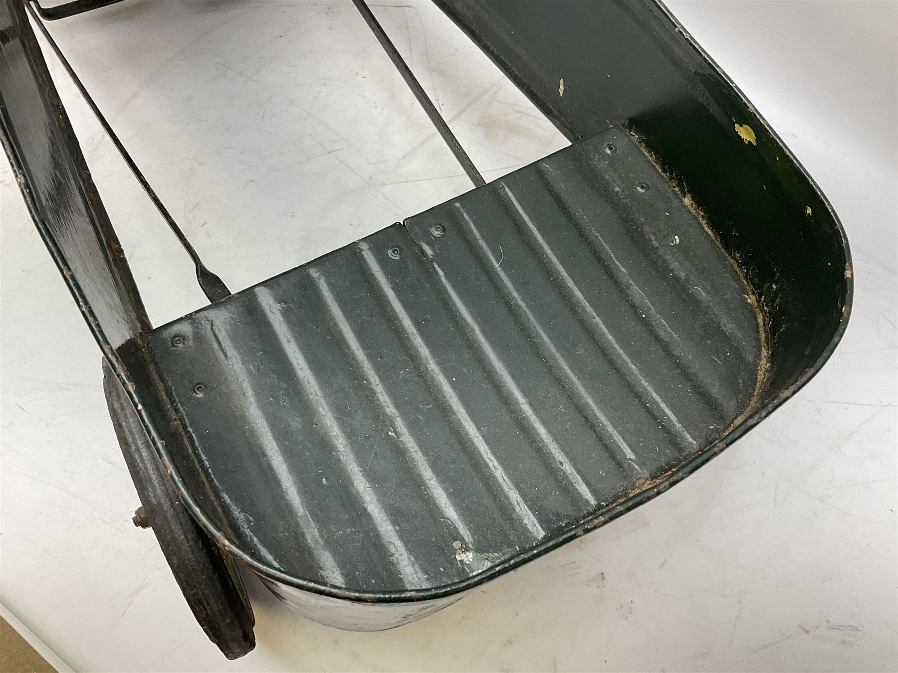 Mid 20th century pressed steel pedal car, the body painted in dark green fitted with pretend radiator to the bonnet, with spoked wheels and rubber tyres, the interior with pedals and steering wheel, L70cm