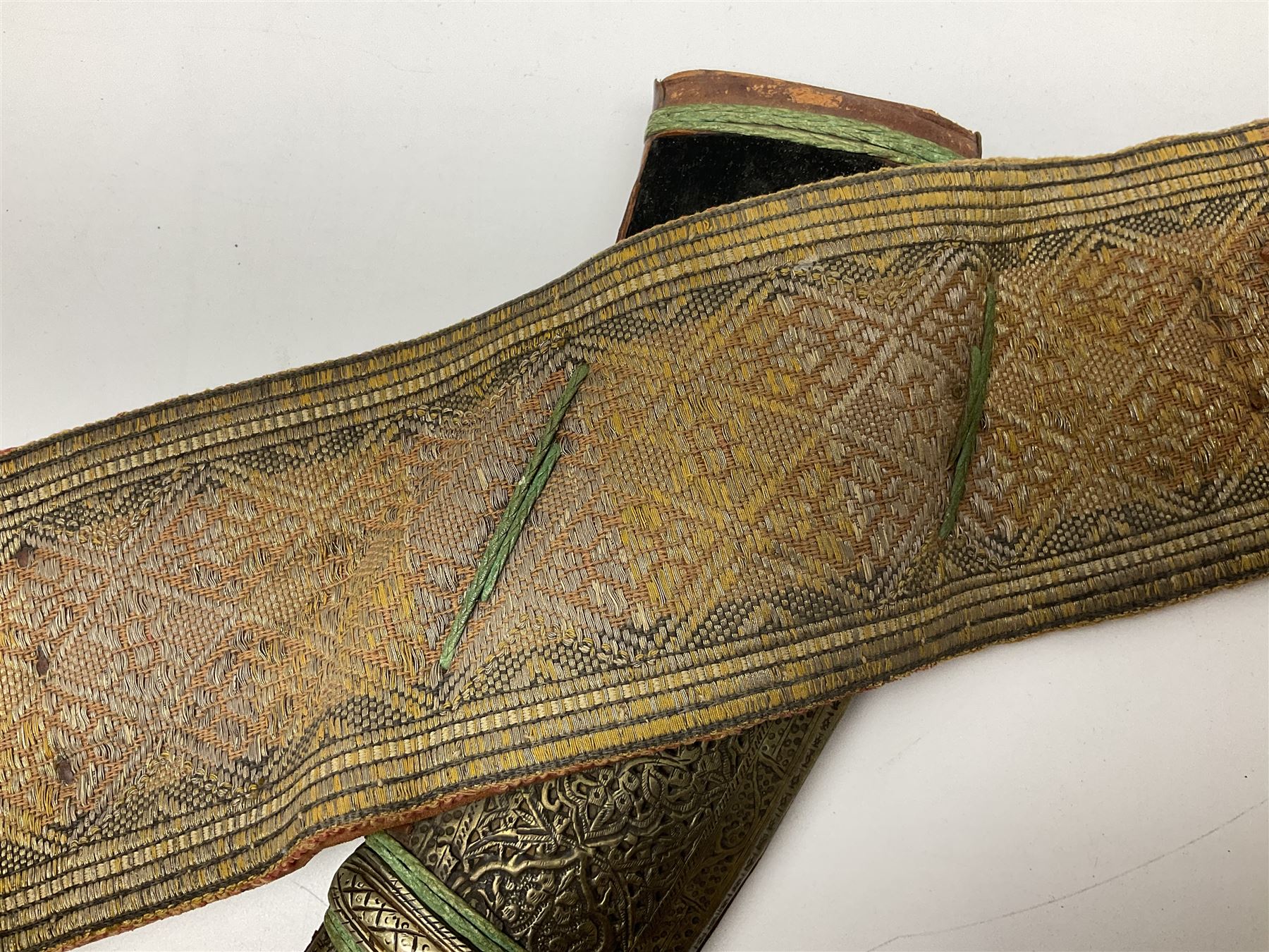 Late 19th century Yemeni Tuza jambiya as worn by religious elite, the 20.5cm curving blade with raised medial ridge, the horn hilt with pique style studwork, in a leather wrapped wooden scabbard with pierced metal mount and leather belt applied with embroidered 'gold' and 'silver' thread work panel; dagger L36cm overall, belt L84cm