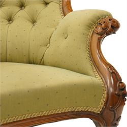 Victorian mahogany framed double ended chaise longue, serpentine button upholstered back with raised scrolled ends, padded arms and stuff-over seat upholstered in green fabric, carved showframe with foliate terminals and scroll supports, on short cabriole legs with brass castors