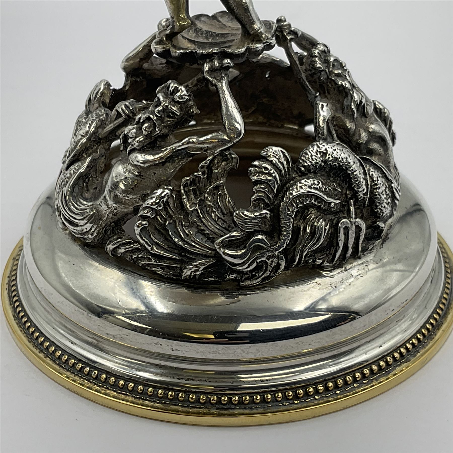 Modern limited edition silver mounted nautilus shell cup, no. 42/150, the pearlescent shell cup with silver-gilt strapwork to rim, upon a stem modelled as a putto supporting a gilt cornucopia and circular domed foot depicting Poseidon amongst swirling waves, hallmarked by St James House Company, London 1980,  H17.5cm