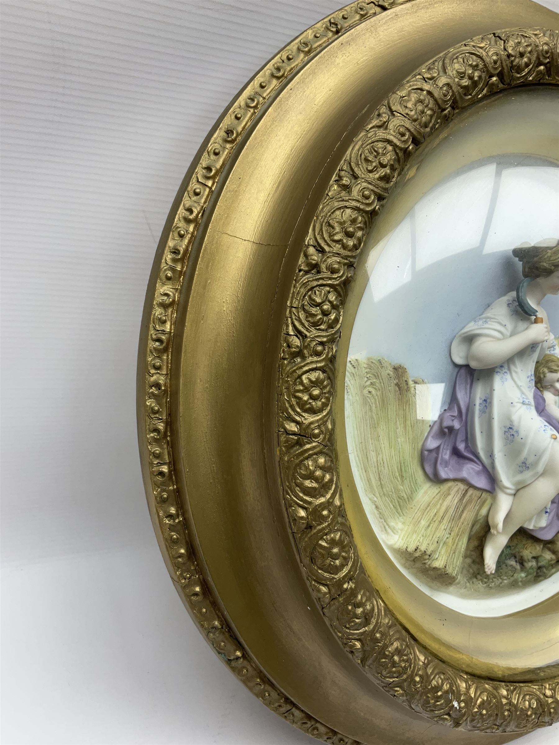 Set of four early 20th century Continental bisque plaques, each of circular form, modelled in high relief as the Four Seasons personified, within gilded circular frames under convex glass, overall D44.5cm