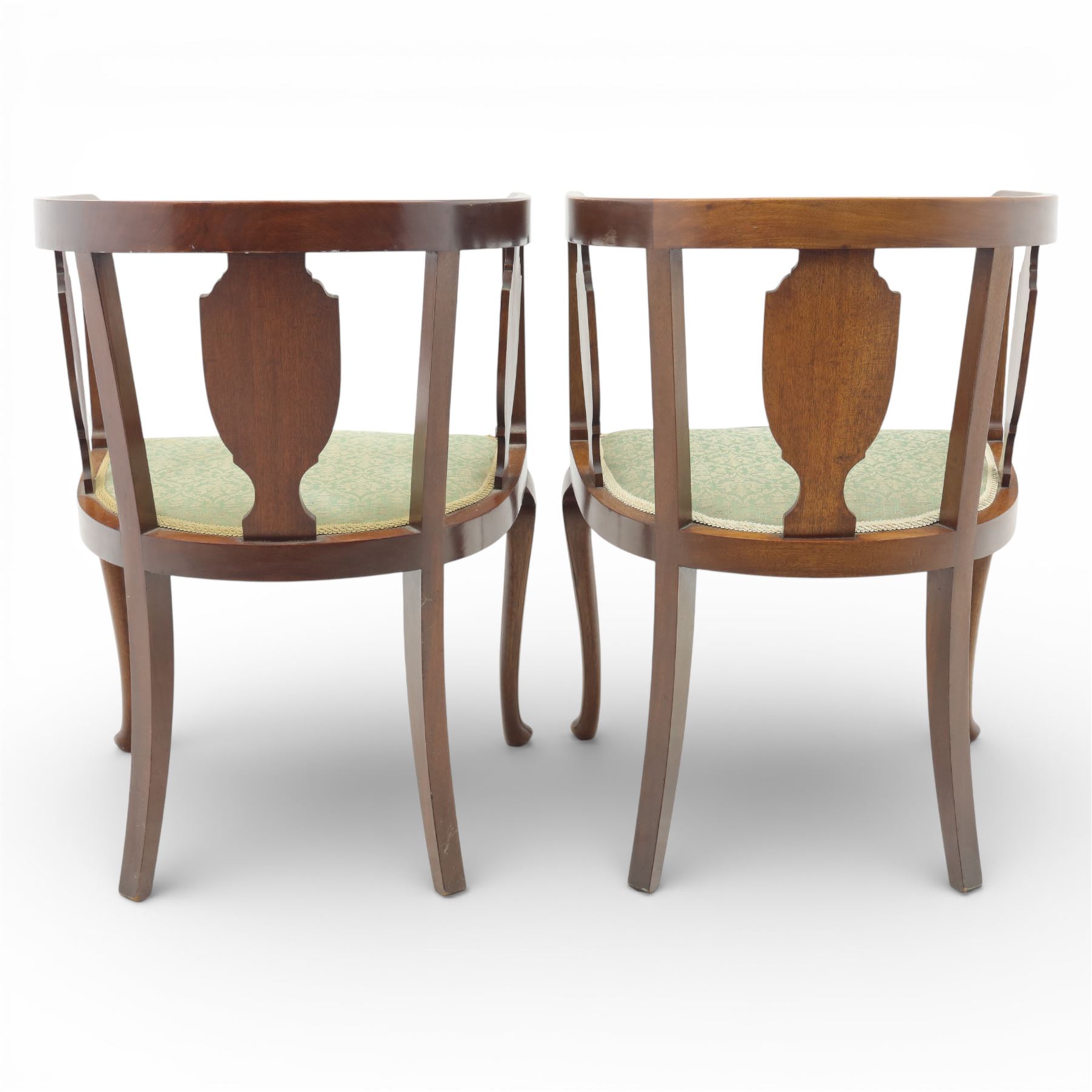 20th century mahogany tub chairs, the arched backs enclosing shaped splat panels and plain uprights, open curved arms flowing into the seat rails, upholstered seats in green foliate patterned fabric, on cabriole legs
