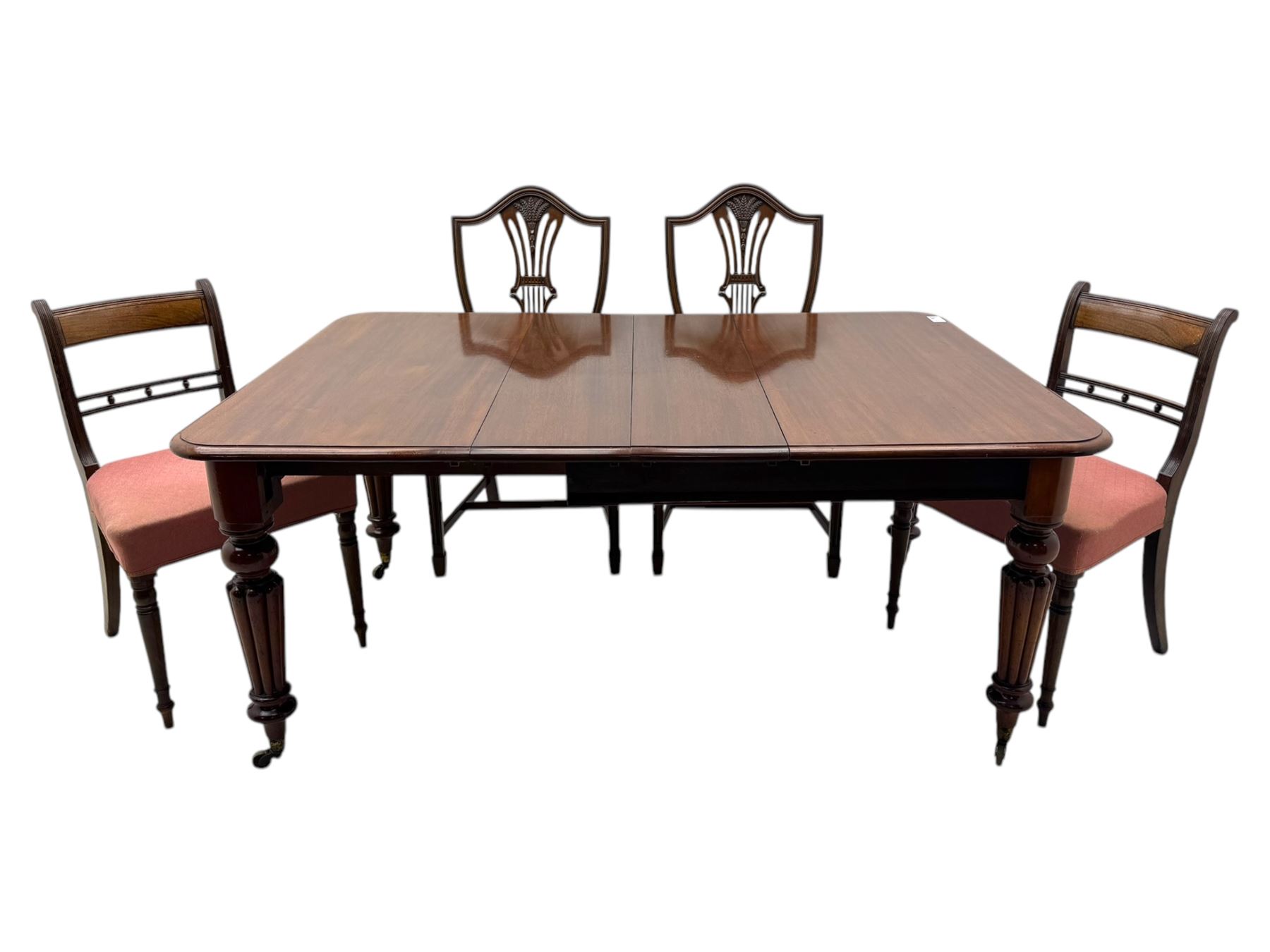 
Late Victorian mahogany extending dining table and four chairs, rectangular top with rounded corners and moulded edge, fitted with two additional leaves, raised on turned and reeded legs with brass castors, with a pair of Victorian mahogany hall chair, with curved top rail and plain splat, padded seat in textured salmon pink fabric, raised on turned and tapering front legs and another pair of early 20th century mahogany dining chair, with shield back and carved pierced splat, serpentine seat rail with striped upholstered cushion, raised on moulded square front legs