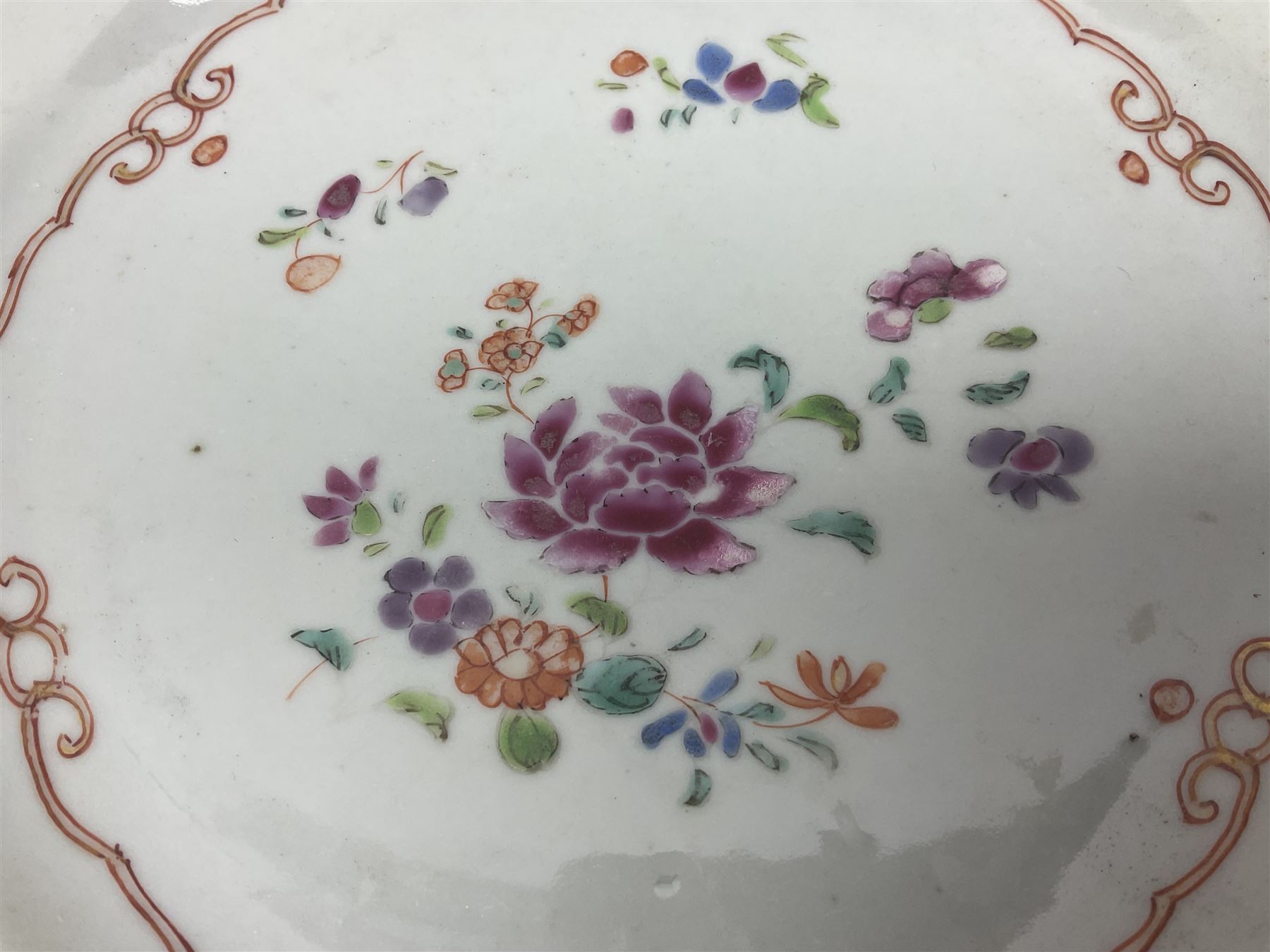Three 18th century Chinese Famille Rose plates, the first example enamelled with blossoming peonies, rockwork and fence, the other two examples of similar design, decorated with blossoming peonies and sprigs within shaped inner borders, each approximately D23cm