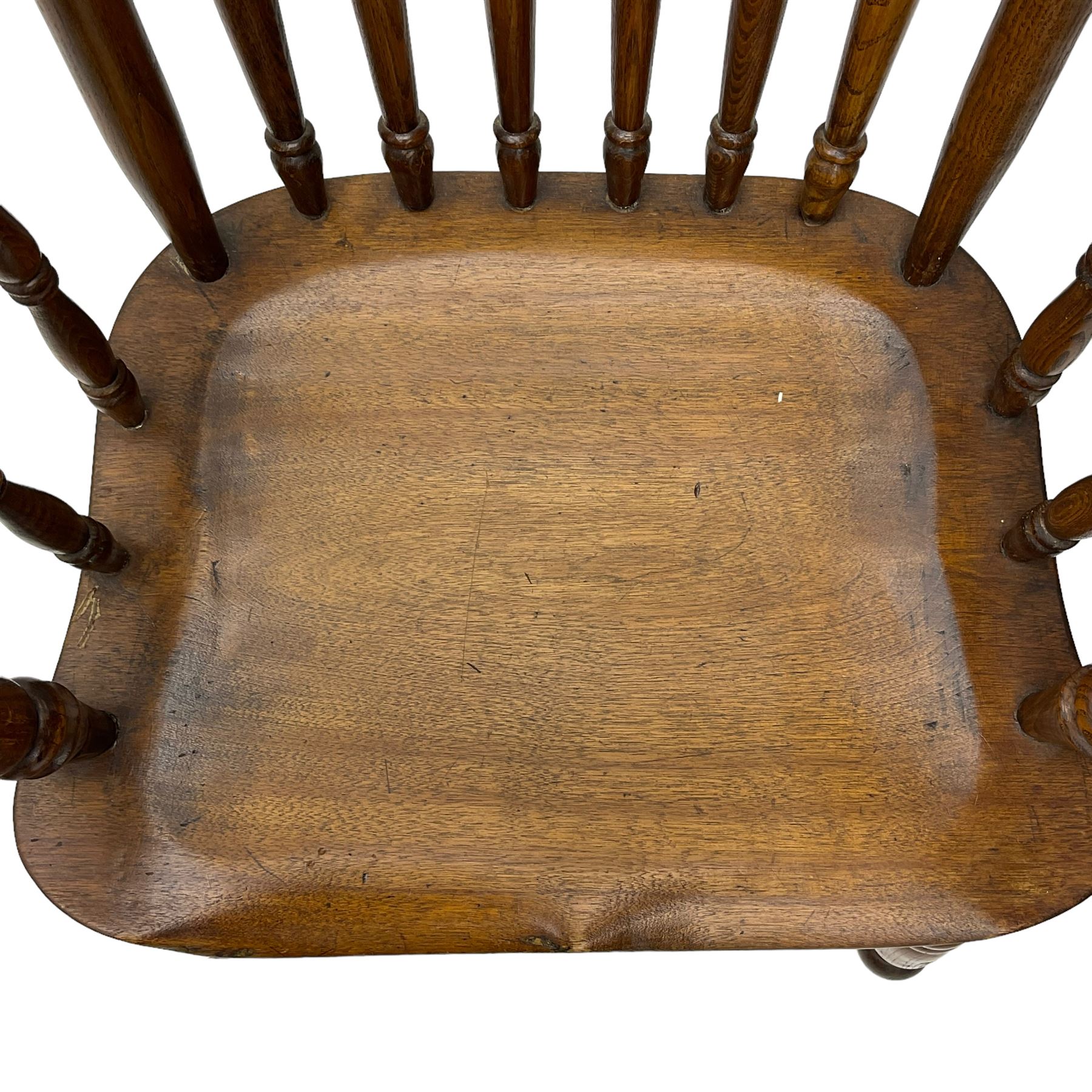 Early 19th century elm farmhouse armchair, the shaped eared cresting rail over tall spindle back, dished seat on turned supports united by H stretchers