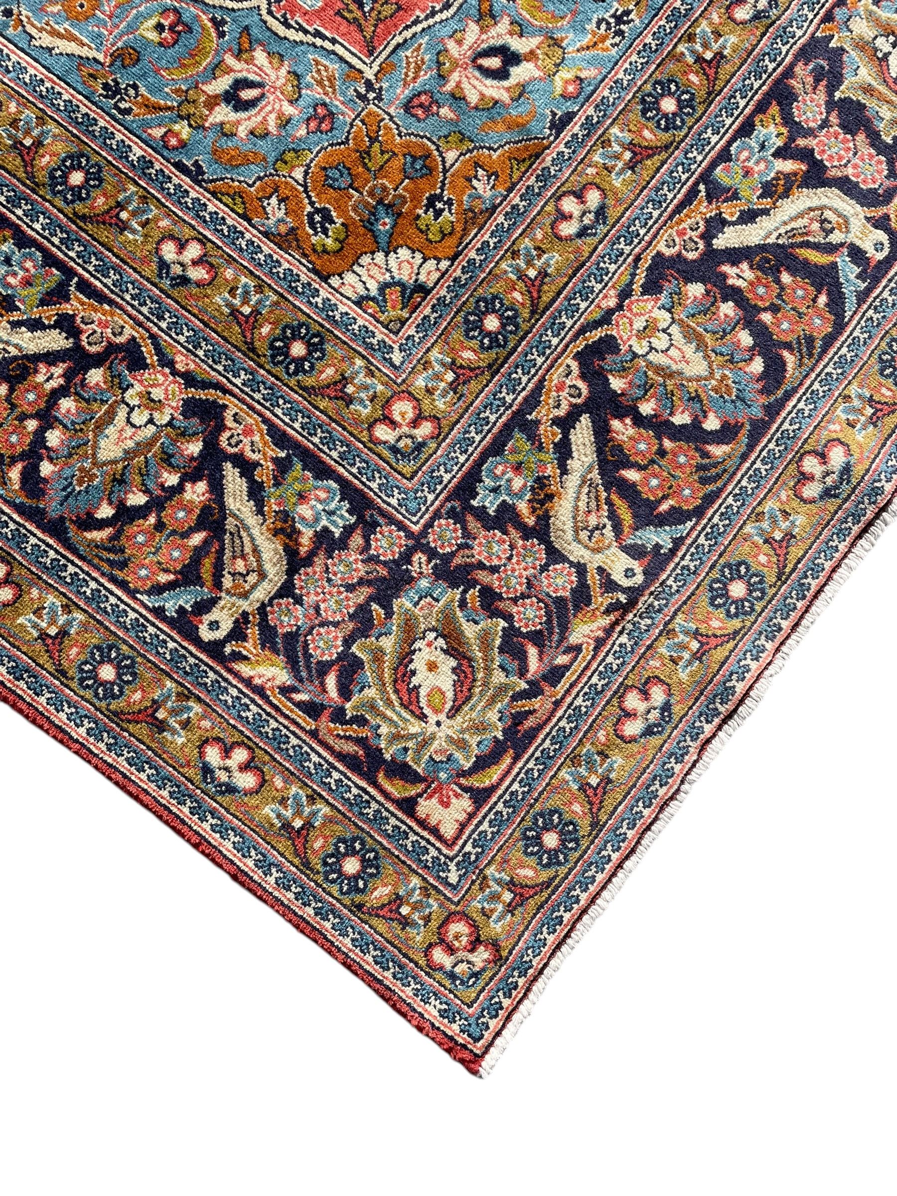 Persian Kashan peach ground rug, central rosette medallion surrounded by trailing branches and flower heads with bird motifs, light blue spandrels with further floral decoration, the main border with repeating palmettes and birds, within guard stripes