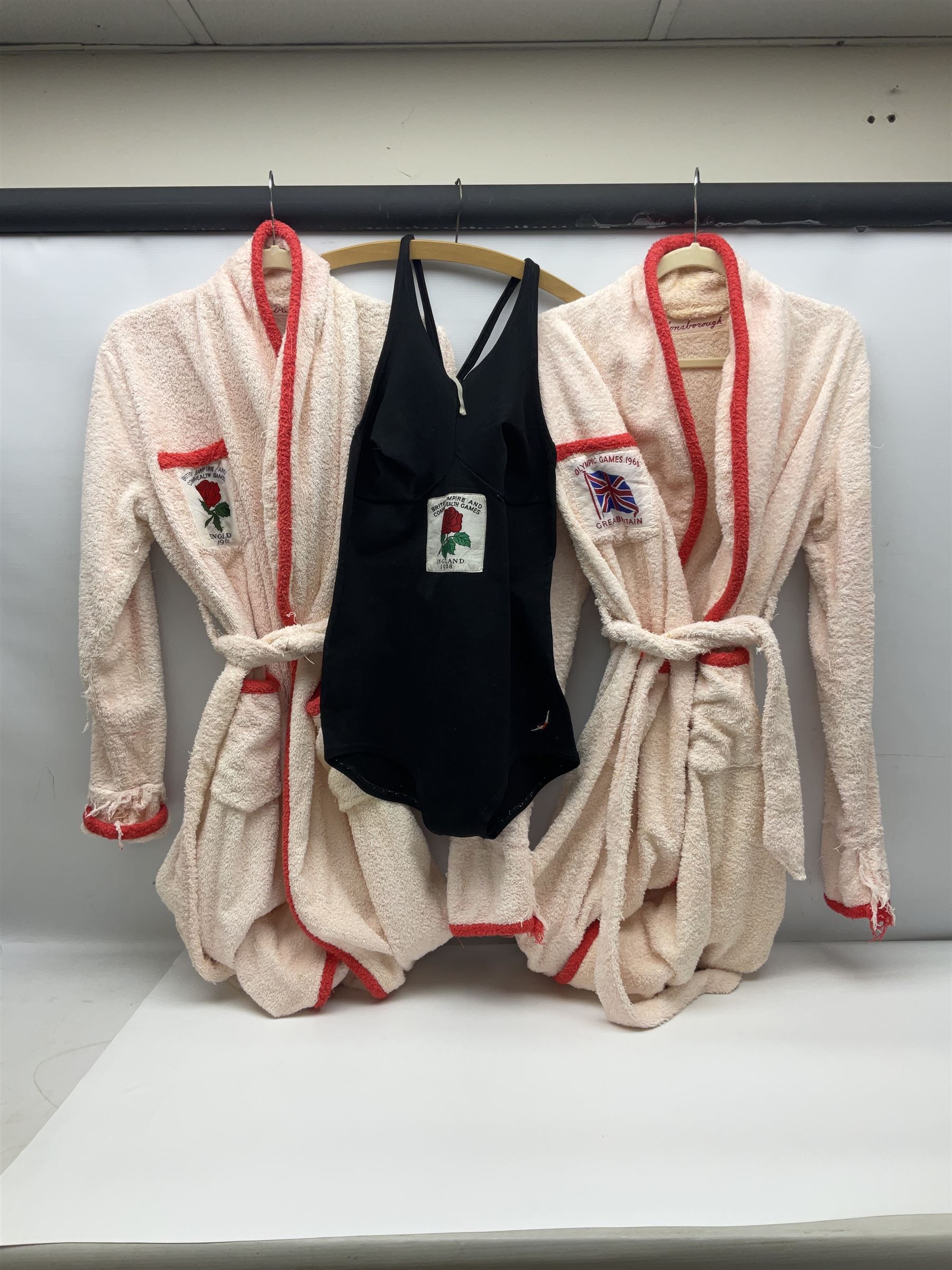 On the direct instructions of Anita Porter nee Lonsbrough Great British Olympic and Commonwealth Games gold medal winning swimmer - collection of early and international memorabilia comprising original Huddersfield Bath Club track suit top bearing eight stitched on cloth badges including British Empire & Commonwealth Games 1958 England Team, YSASA, North Eastern Counties ASA, ESSA Division 3,  English Schools Swimming Association winner etc
The swimming costume Anita wore at the 1958 Commonwealth Games in Cardiff, her first major championships, where she won two gold medals. The grey elastic on the sides, in those days, she would use to make it tighter and more streamlined.
Blue track suit from the 1960 Olympics which she wore on the podium receiving the gold medal.
1960 pool side towelling robe used at the Rome Olympics (interesting to note her name is spelt wrong on the embroidered label).
1962 Commonwealth Games pool side towelling robe used in Perth Australia when winning three Gold medals. 
It was also this year she became BBC Sports Personality of the year, the first female to do so.
Her 'lucky' pool side towel which she took with her to every event she competed in and which can be seen round her neck in many official celebratory photographs. Copies of some of these photographs are included for identification.
In addition there are two souvenir programmes of an evening event to honour Anita at The Theatre Royal Huddersfield and she has kindly signed the front cover on one of these.