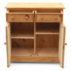 Contemporary pine storage cabinet, the rectangular top with rounded corners, over twin drawers and panelled cupboard doors, fitted with turned knob handles, plinth base