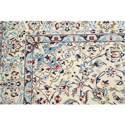 Central Persian Nain hand-knotted rug, ivory field with central medallion in tones of indigo and blue, issuing vinery, palmettes and floral sprays with conforming spandrels, dark blue main border of floral vinery and stylized palmettes, framed by multiple guard borders, with cotton fringe ends 