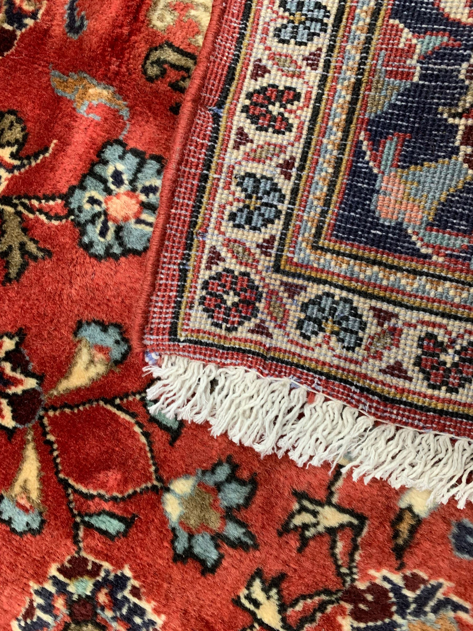 Persian Ardakan crimson ground rug, the field with shaped floral design medallion surrounded by curled leafy branches, scrolling border with stylised plant motifs