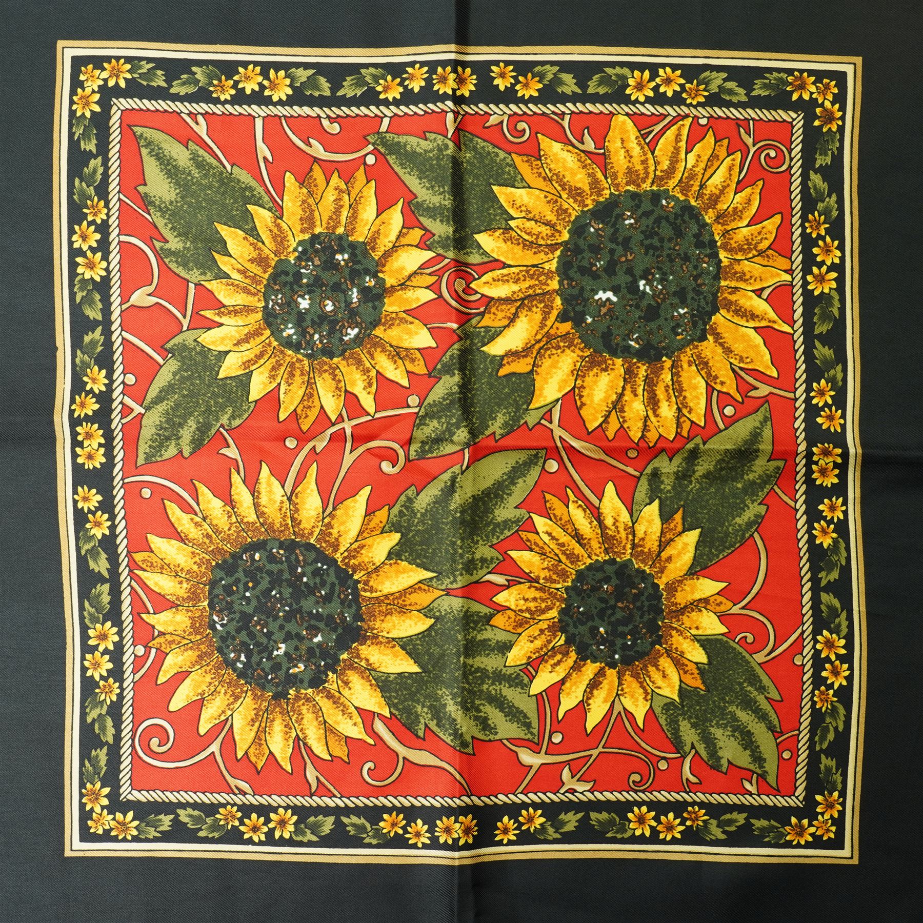 Hermès silk carré scarf, the black ground with central sunflower motif framed by ornate baroque panels and tassel borders in red, gold and yellow tones, signed Hermès Paris to the corner, hand-rolled edges, 90cm x 90cm