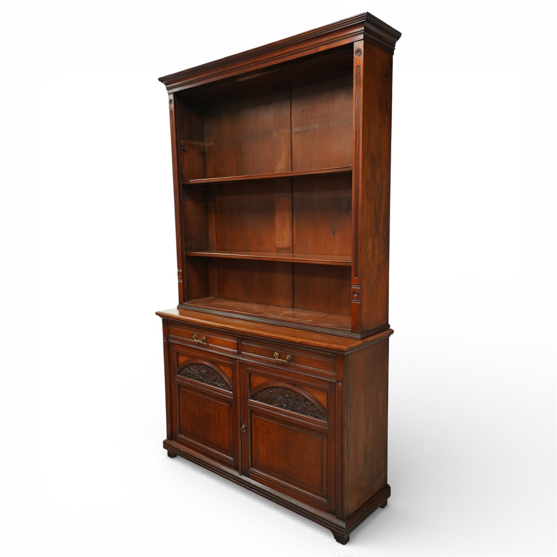 Late Victorian tall walnut open bookcase on cupboard, projecting cavetto cornice over reeded and fluted uprights moulded with roundel motifs, flanking two adjustable shelves, the base fitted with two drawers over panelled cupboards, carved with oakleaf and acorn motifs and grapevines, on bracket feet