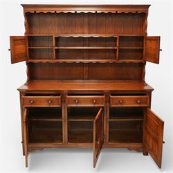 20th century oak dresser, moulded cornice above open plate rack with shaped frieze, flanked by two cupboard doors enclosing shelving, the base fitted with three drawers over three fielded panel cupboard doors, raised on bracket feet