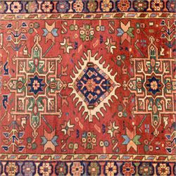 North West Persian Karajeh hand-knotted runner, madder red field, decorated with a vertical sequence of bold geometric medallions, interspersed with stylized floral and tribal motifs, framed by a dark ground border of angular palmettes and rosettes with multiple guard stripes, with cotton fringe ends 