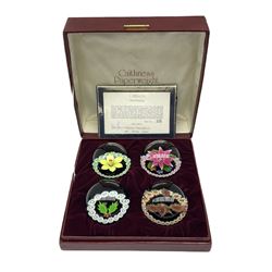Set of four Caithness paperweights titled Four Seasons, in presentation box with certificate, designed by Colin Terris and made by William Mason, each internally decorated with a seasonal flower within a millefiori cane work garland, numbered 128 of 500