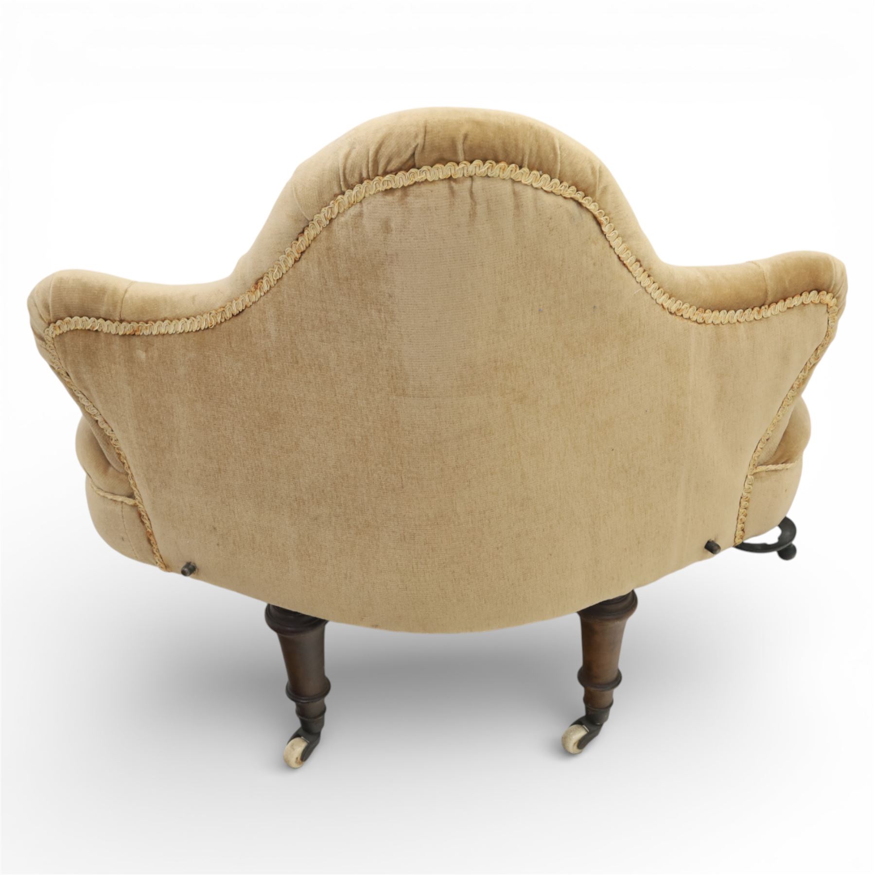 20th century pair of bedroom chairs upholstered in buttoned taupe velour, each of slipper chair form with low wraparound back and deep seat, the backs button tufted with padded wings, raised on turned front supports with castors