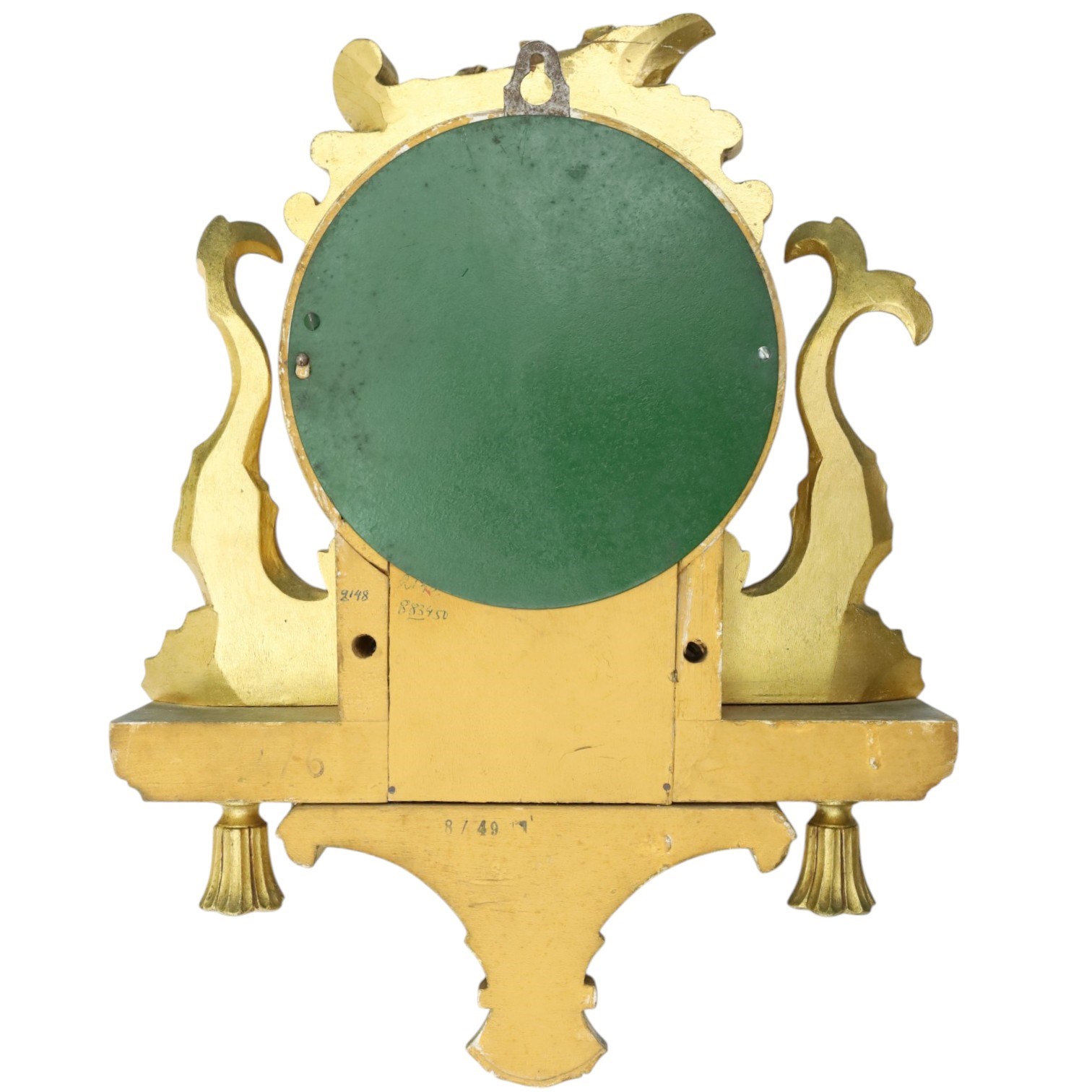 20th century Continental giltwood wall clock, circular dial with Arabic numerals and pierced gilt hands, within a carved case surmounted by a scrolling crest and flanked by stylised dolphins, above a shaped shelf with tassel pendants and a foliate terminal, pendulum missing
