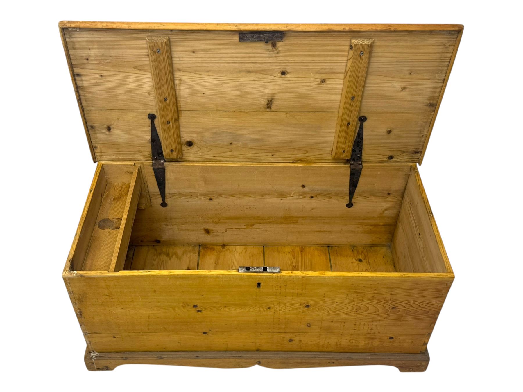 Late 19th century stripped pine blanket box, rectangular hinged lid enclosing main compartment with fitted candle box, wrought iron strap hinges and lock, black-painted side handles, on a shaped plinth base