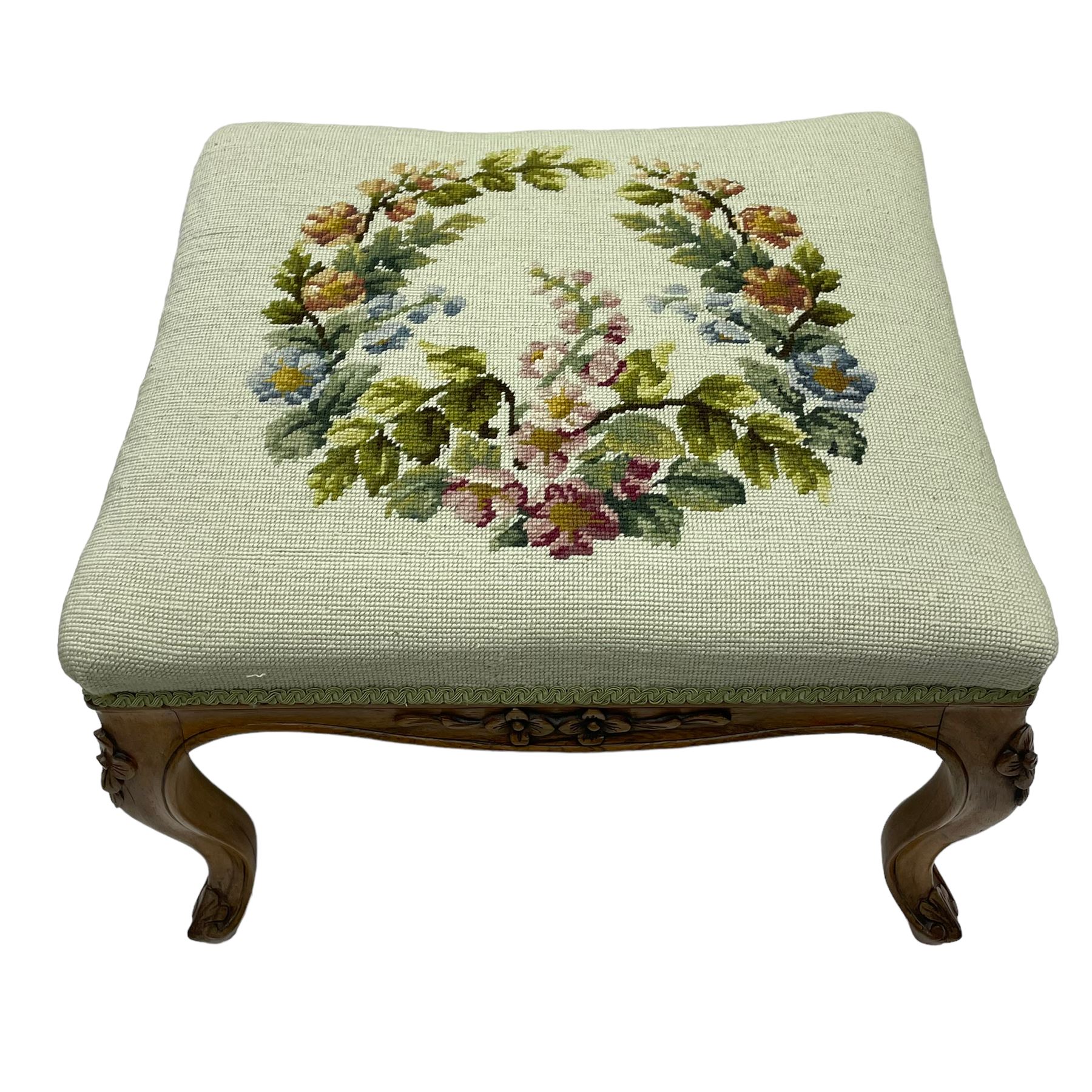 19th century French walnut dressing stool, rectangular seat upholstered in a floral needlework tapestry top, shaped apron with applied carved flower heads, on cabriole supports with acanthus carved feet