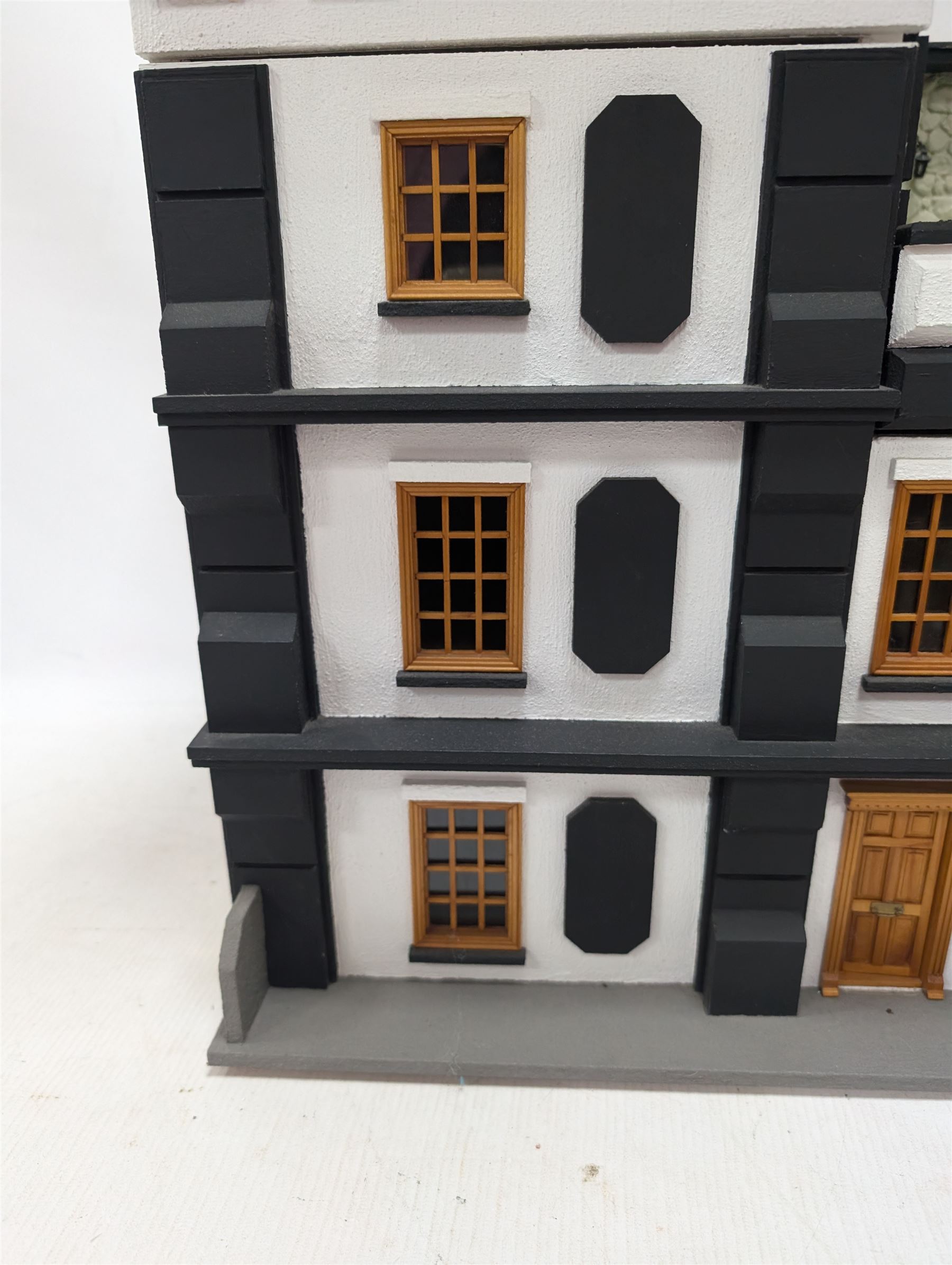 1:24 scale four-storey tudor-style dolls house, with black and white exterior, balcony garden, glazed panelled windows and wooden shingle roof, with decorated interior and wired fireplaces and lighting, H65cm, W58cm, D31cm, 