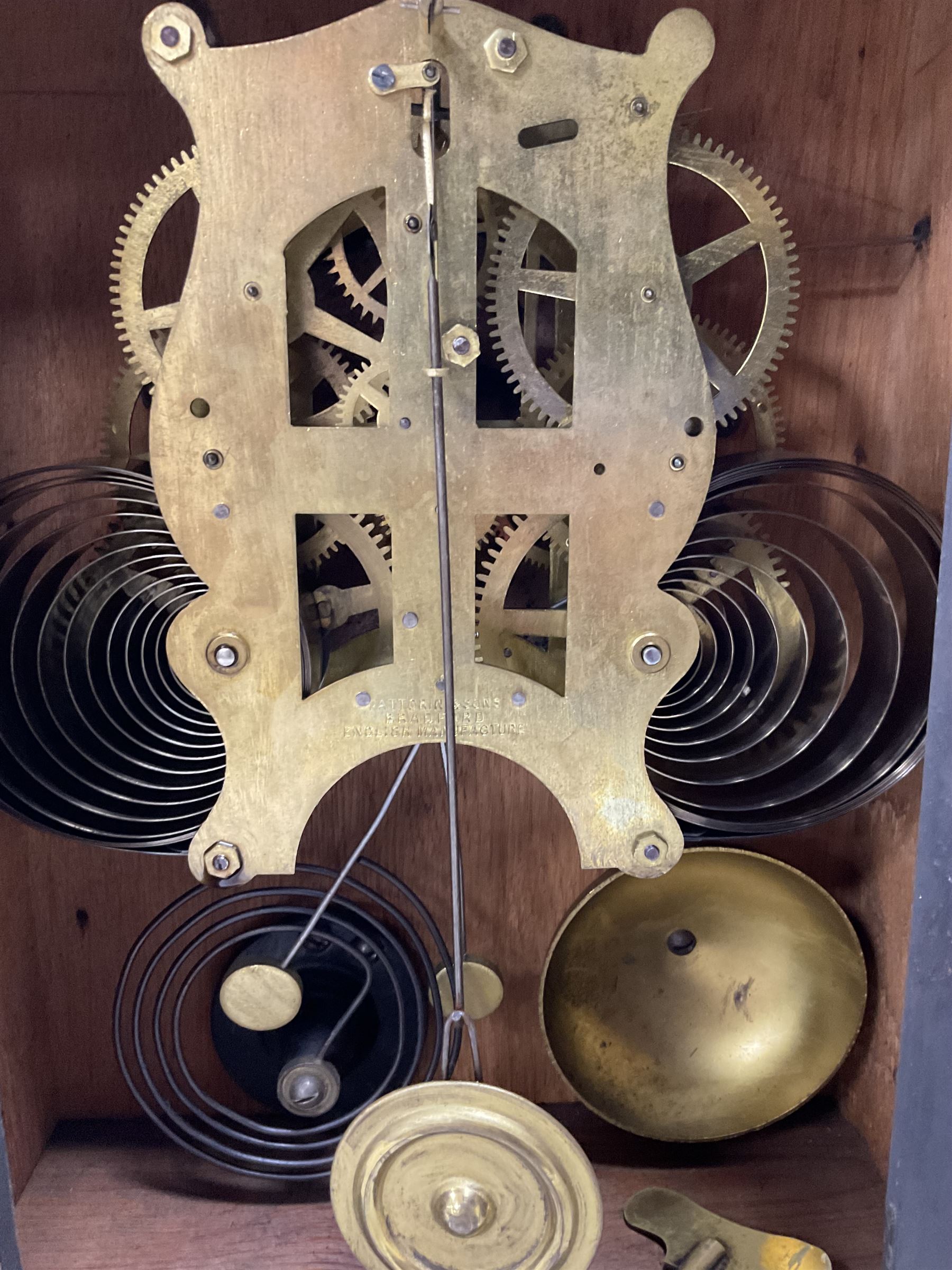 Fattorini of Bradford - oak cased early 20th century mantle clock with alarm, rectangular case with a broken pediment, turned finial and matching carved pilasters to the front, on a broad stepped plinth with a flat base, circular dial with an ivorine chapter within a decorative gilt bezel, Arabic numerals , spade hands and alarm setting disc to the centre, two train spring driven movement striking a coiled gong and bell. With key and pendulum. 