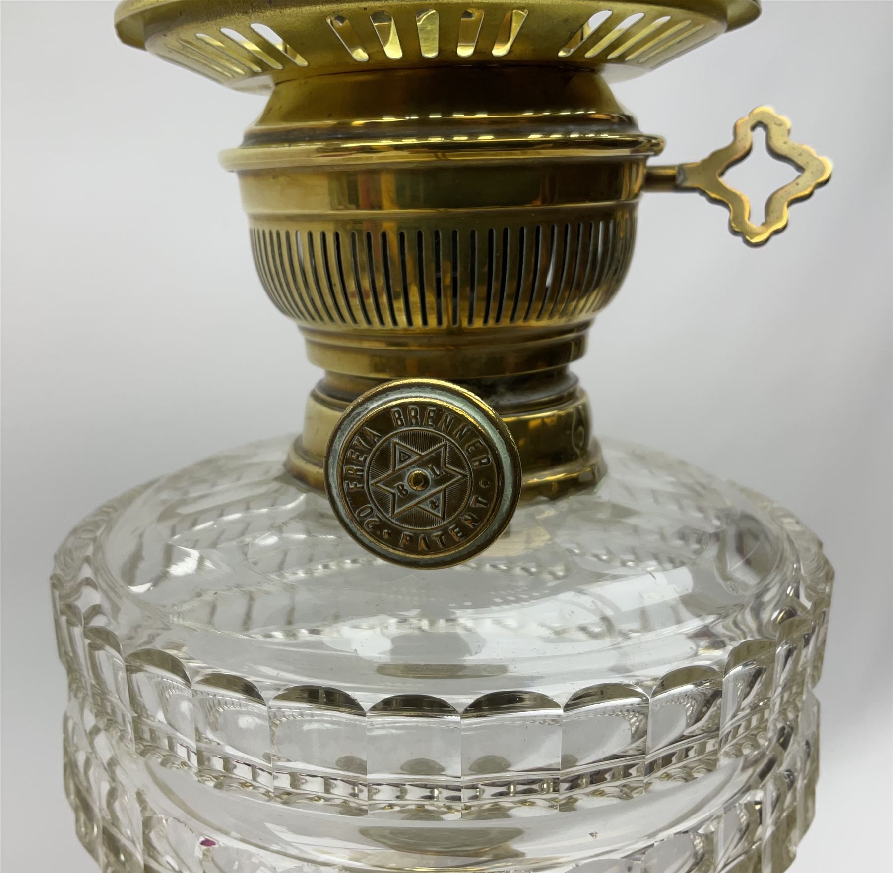 Victorian brass oil lamp, the square stepped base leading to a Corinthian column supporting a part slice cut clear glass reservoir, burner, clear glass chimney and foliate etched glass shade with amber rim, overall H80cm