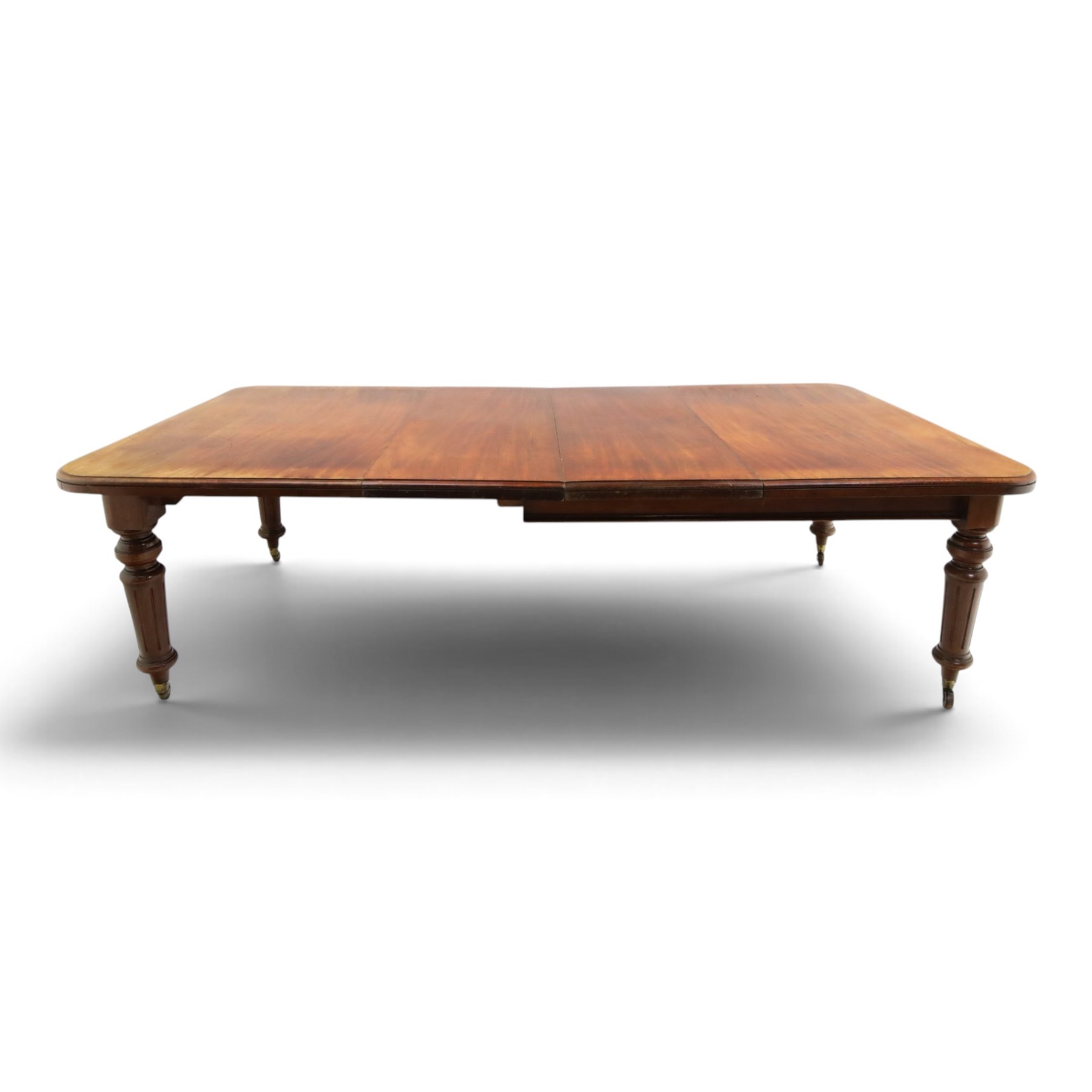 19th century mahogany extending dining table, rectangular top with rounded corners raised on turned and fluted supports with brass cups and castors, with two additional leaves; with set of eight (6+2) Regency design mahogany dining chairs, spiral-reeded back-bar over drop-in seats and sabre supports (W54cm H85cm)