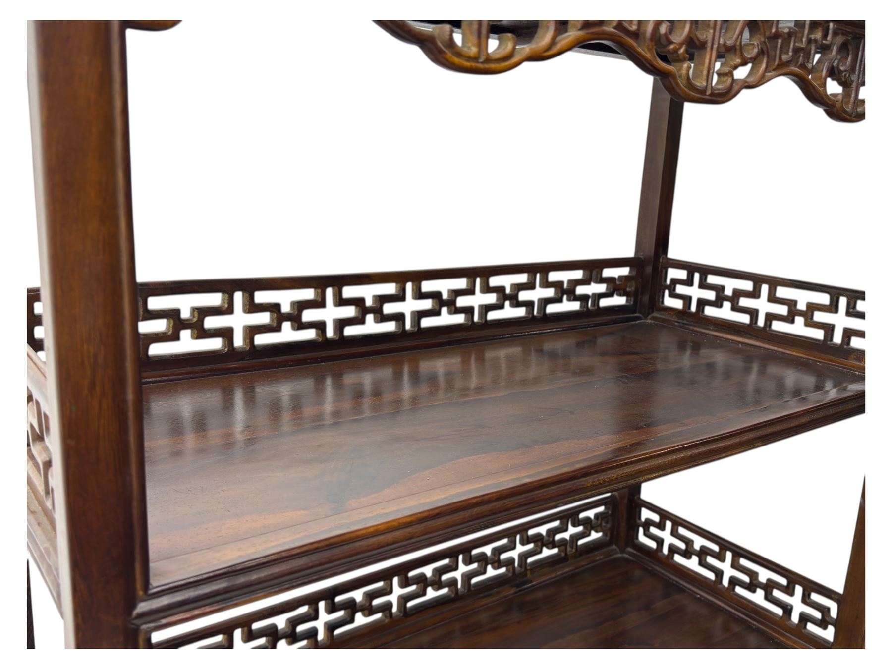 Early 20th century Chinese hardwood display étagère bookcase, the rectangular open tiered frame with pierced frieze and geometric openwork gallery to each shelf, fitted with two short drawers carved with stylised lotus motifs, supported on square uprights with pierced apron and integral gallery rails