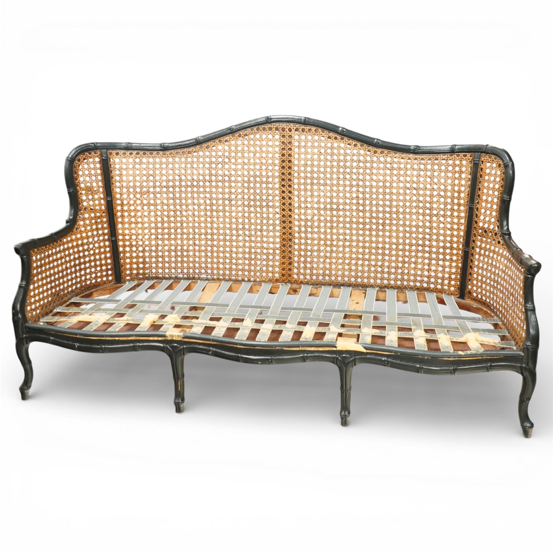 Early 20th century French bergère settee, the shaped caned back flanked by caned sides and scrolling arms, moulded beech frame with dark painted finish, serpentine seat rail with webbing, on cabriole legs with pad feet