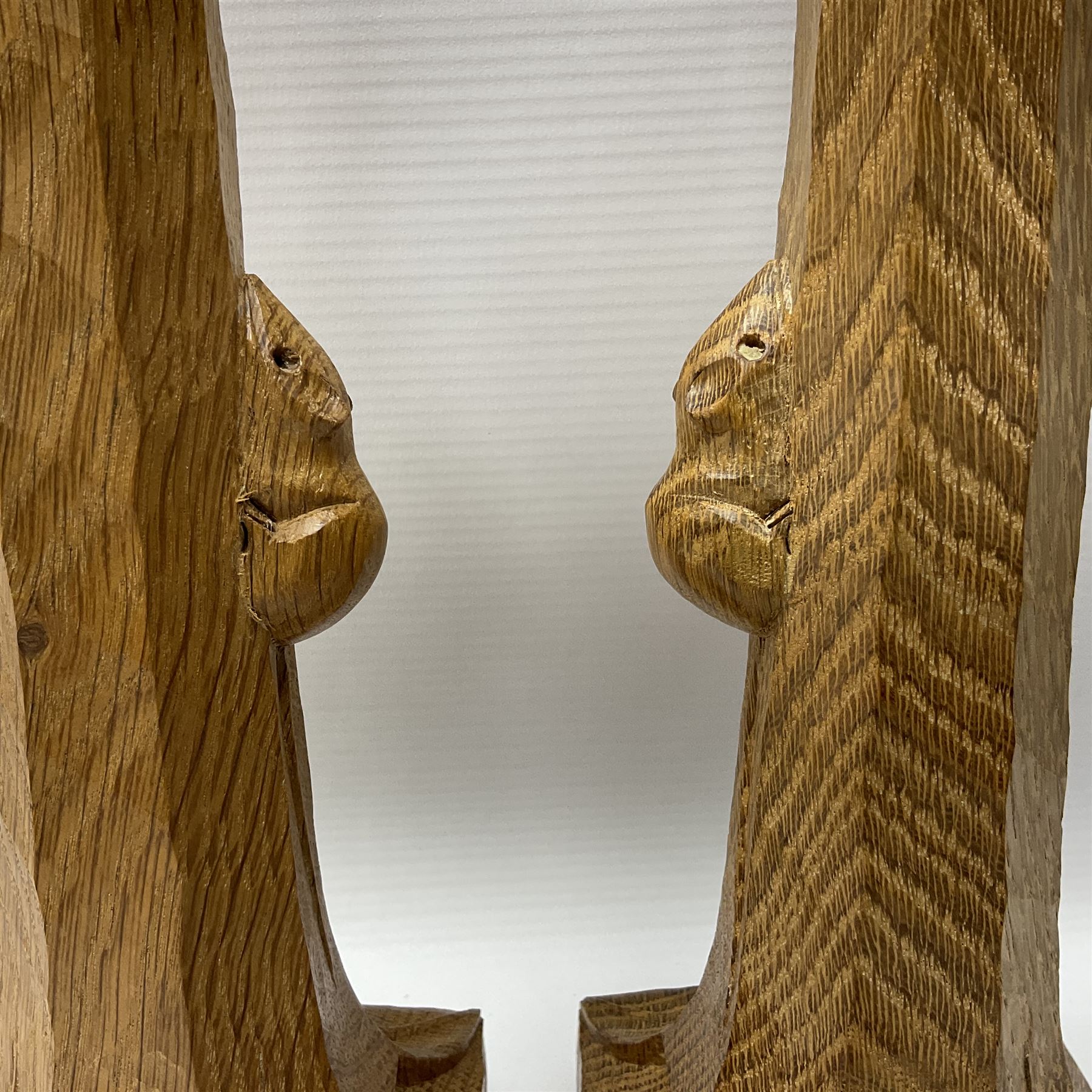 Mouseman - pair of tooled oak candlesticks, wrought iron sconce with drip tray over tapered octagonal column carved with mouse signature, terminating to stylised leaf carved square base, by the workshop of Robert Thompson, Kilburn
