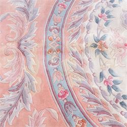 Large late 20th century Aubusson style wool carpet, peach and pastel toned field with central floral medallion enclosing scrolling acanthus and and foliate sprays, surrounding field decorated with further stylized foliage and and floral ornament, within shaped reserves and indigo corner spandrels, enclosed by narrow guard border, cotton fringe ends