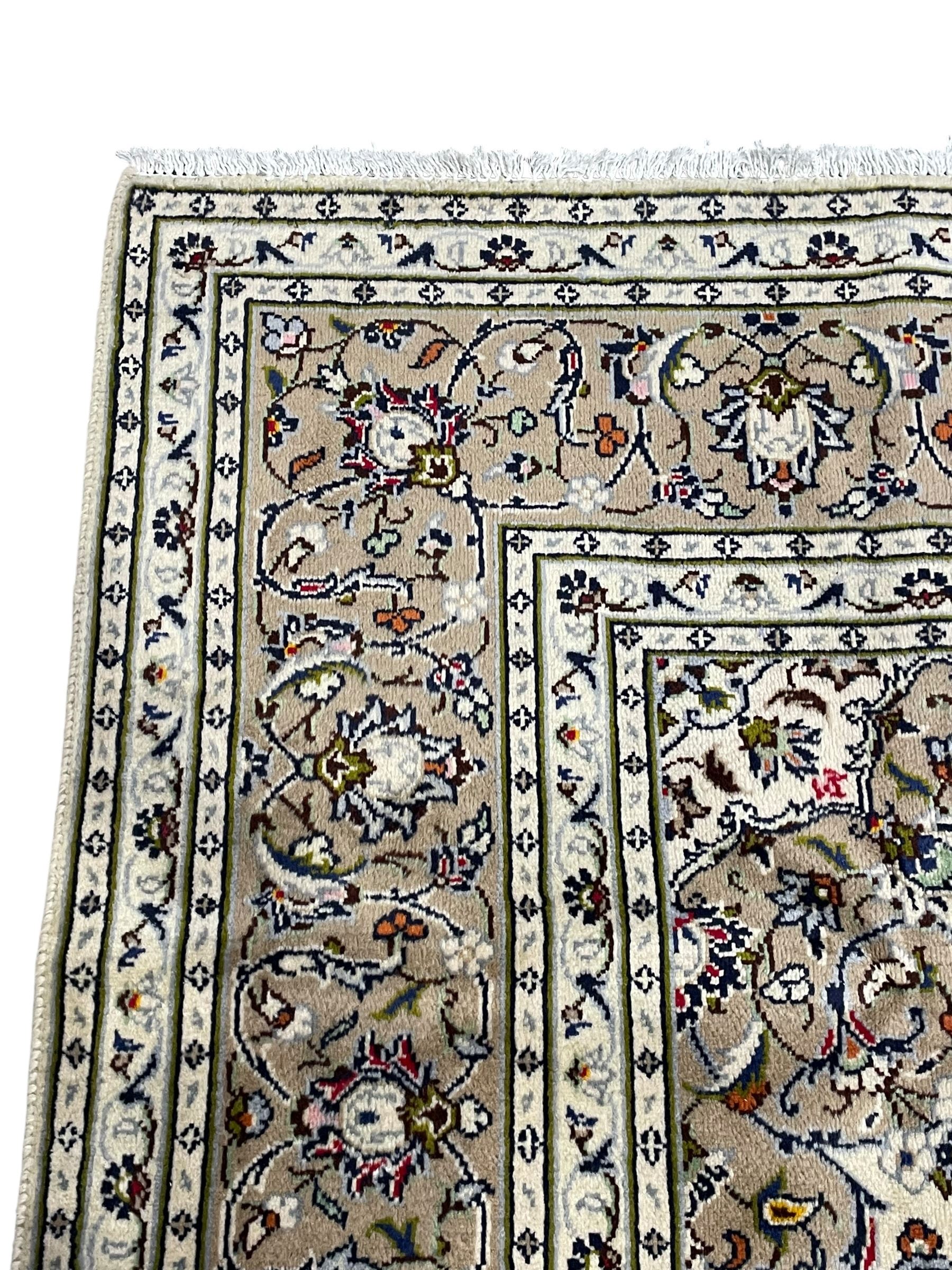 Persian Kashan ivory ground rug, central pointed rosette medallion surrounded by scrolling branches and stylised flower heads, the border with scrolling pattern decorated with palmettes, within guard stripes