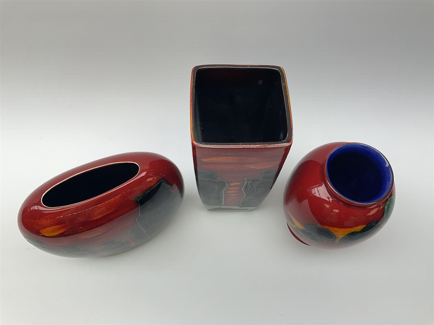 A Poole Pottery vase, of ovoid form decorated with green and yellow forms upon a red glazed ground, H20cm, together with two Anita Harris Art Pottery vase, with similar decoration. 