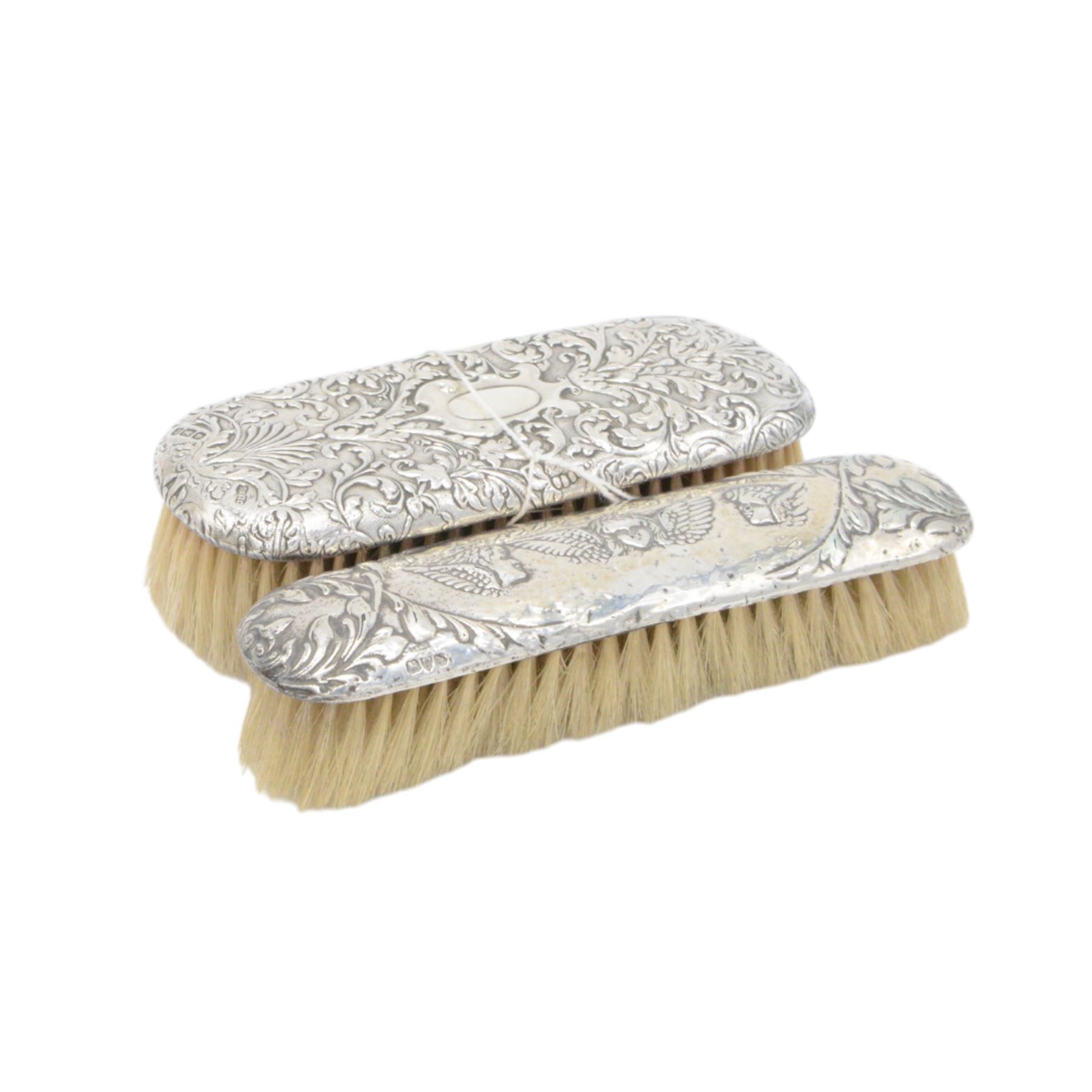 Group of silver mounted dressing table items, to include dwarf candlestick, with embossed ribbon decoration, comb holder, jar lid and six clothes brushes, all hallmarked 