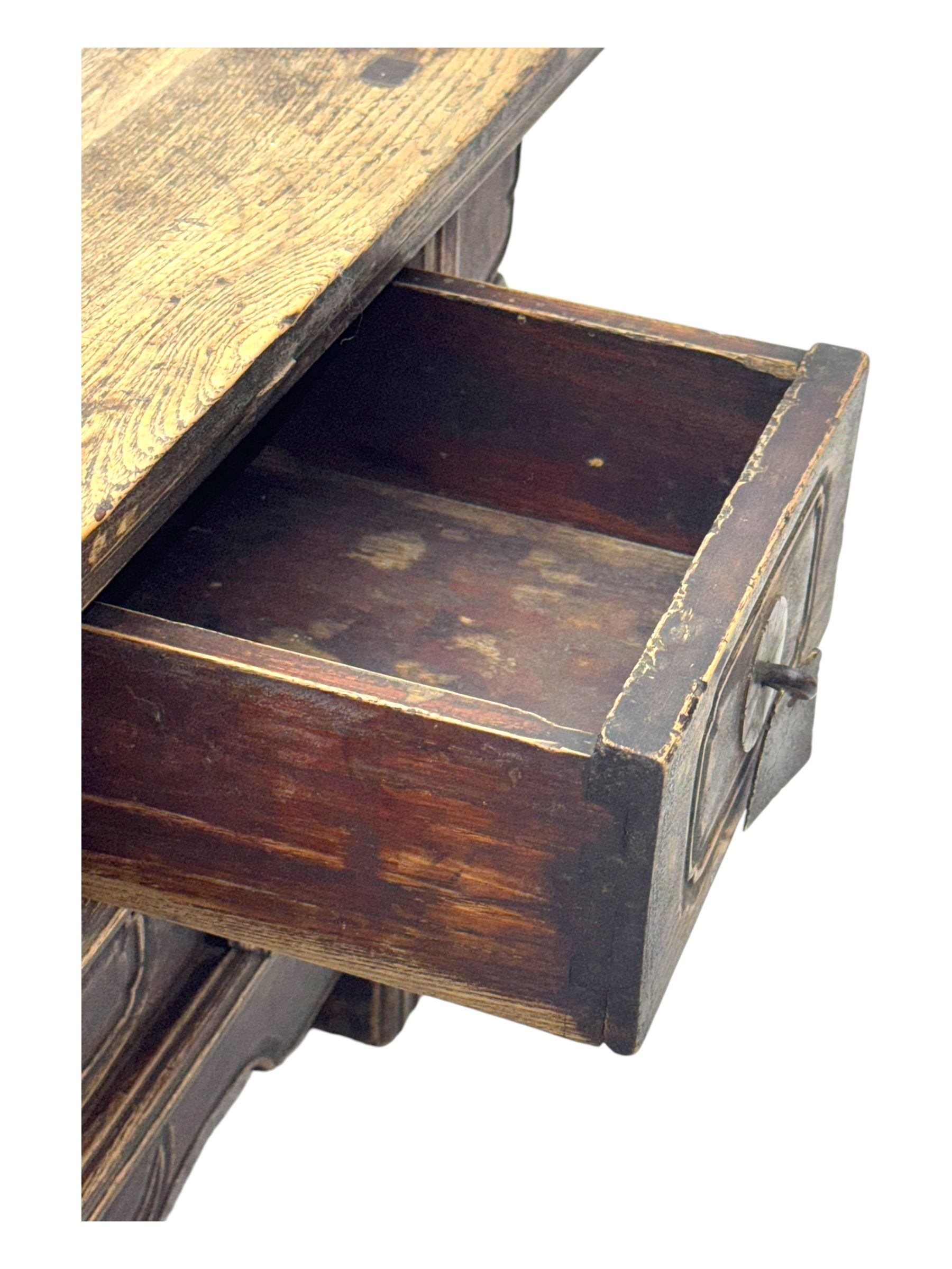 Mid-19th century elm low altar table, rectangular top with scrolled ends, fitted with three small drawers, pierced and scroll carved brackets, on square moulded supports 